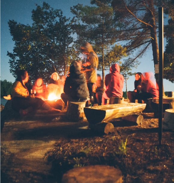 Girls sit around a bonfire