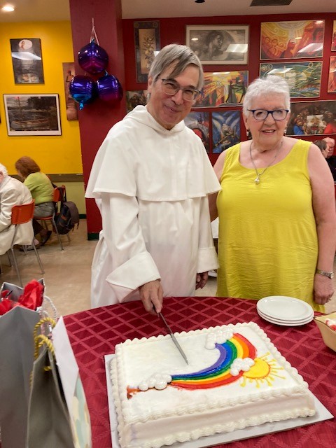 Photo of a man in religious garb and a woman with a cake